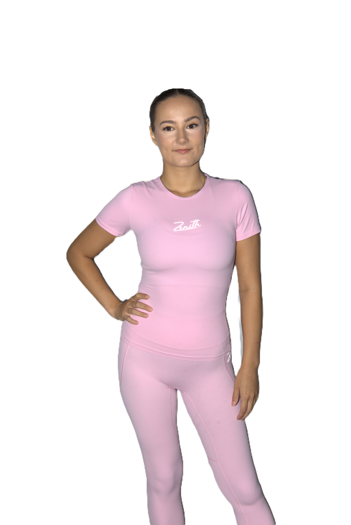 A woman modeling a light pink athletic t-shirt and matching leggings set with a white script logo on the chest, set against a plain white background.