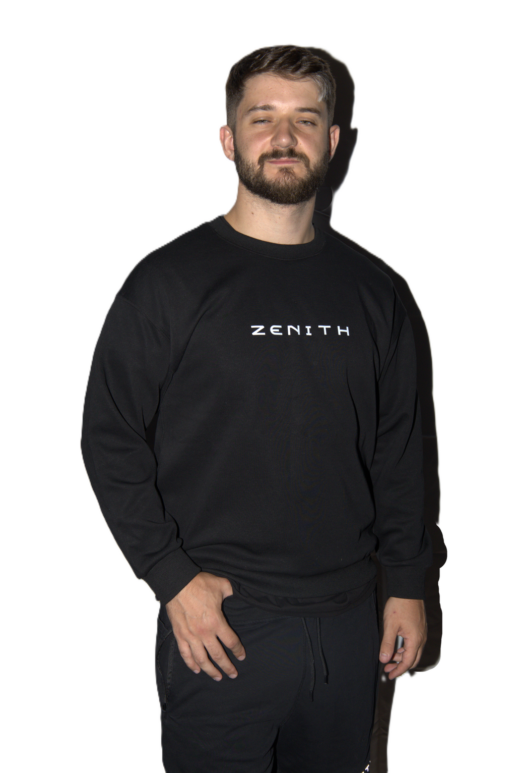 A man wearing a black long-sleeve sweatshirt with the brand name 'ZENITH' printed in white across the chest, paired with black sweatpants, set against a plain white background.